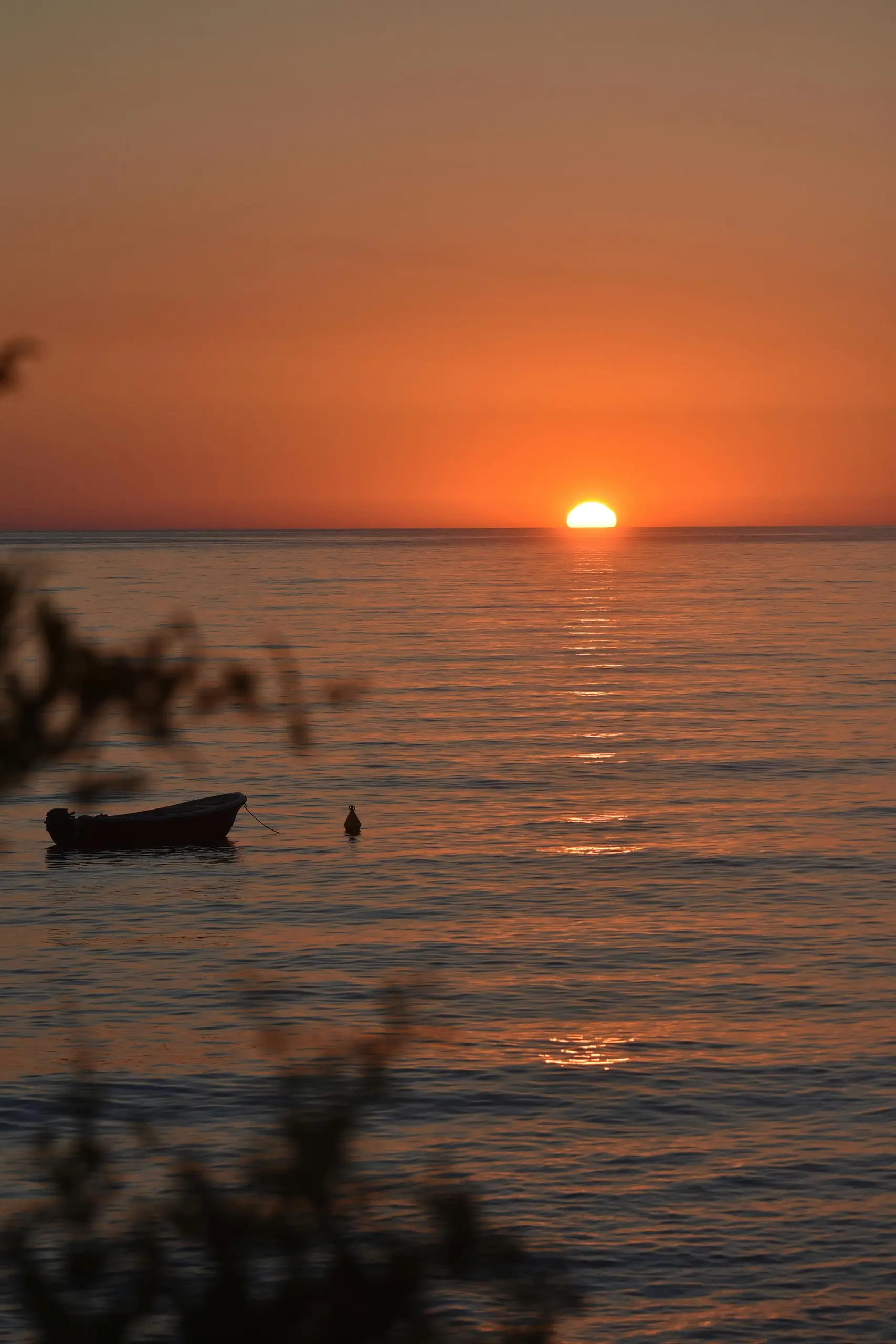 A small boat floating on water during sunset.